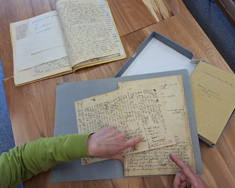 Pśepódanej rukopisa (módra mapa) pśed pśewóstajenim Marjany Domaškojc w Serbskem kulturnem archiwje © Serbski institut (2024)